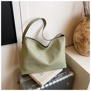 Detail of green woven tote bag with square texture placed on a metallic suitcase