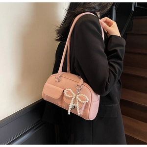 Detail of pink pillow shoulder bag with lychee texture and pearl bow charm