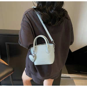 Rear view of a model wearing a light blue lychee pattern leather bucket bag with heart charm