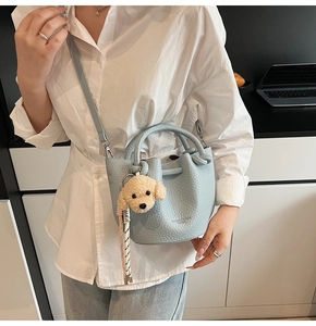 Close-up of light blue litchi grain bucket bag with a cute teddy bear plush charm