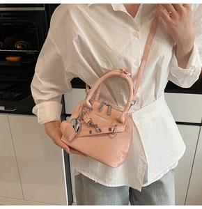 Détail du sac à main rose en cuir verni avec breloque cœur et détails de chaîne