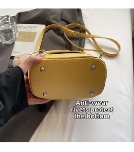 Détail du fond d'un sac en cuir jaune avec quatre rivets métalliques de protection
