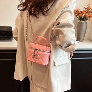 Close-up of pink quilted mini crossbody bag featuring heart charm and chain strap detail