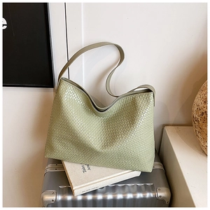 Macro shot of light green woven tote bag with intricate leather texture detail