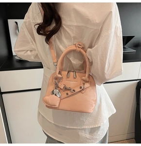 Détail du sac à main rose brillant avec chaîne argentée et breloque en cœur