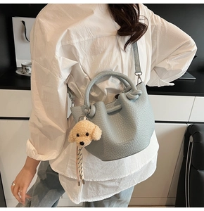 Detail of light blue bucket bag with lychee texture and cute plush puppy charm