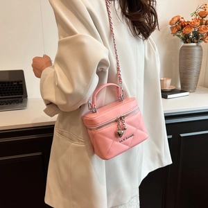 Close-up of pink quilted chain bag with silver heart charms and metal logo details