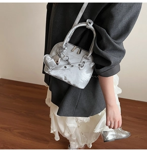 Sac bandoulière argenté métallisé avec pendentif cœur porté par un mannequin