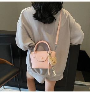 Pink lychee leather mini bucket bag shown on person with plush bear and ribbon charm