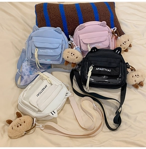 Détail de sacs bandoulière oreilles de chat colorés avec pendentifs ours et poches
