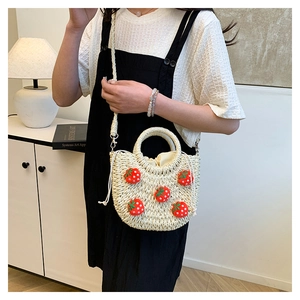 Detail der handgewebten Strohtasche mit gehäkelten Erdbeeren und Kordelzugverschluss innen