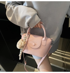 Sac à main rose en cuir grainé avec charm en peluche, ruban rayé et détail de la poignée