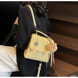 Detail of yellow glossy PU backpack with star buckles and a plush bear charm on a model
