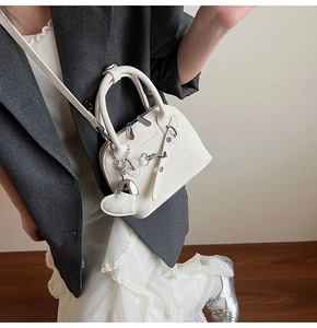 Gros plan du sac coquille blanc brillant avec breloque cœur et détails métalliques