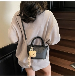 Vue arrière du mannequin portant un sac seau noir en cuir avec pendentif ours en peluche