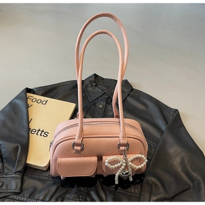 Macro detail of pink lychee leather texture with pearl bow and heart charm on a shoulder bag