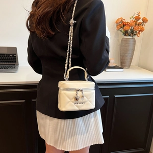Quilted white box bag with heart zipper pull shown from a model's back perspective