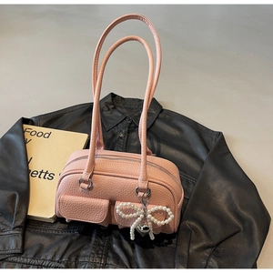 Detail view of pink pebble leather shoulder bag with pockets and pearl bow charm accessory