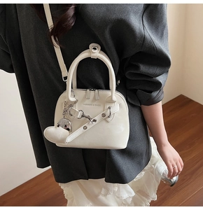 Détail du sac à main coquille crème avec pendentif cœur et inscription fashion