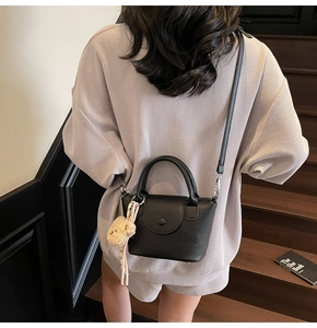 Détail d'un sac à main noir en cuir litchi avec pendentif d'ours en peluche mignon
