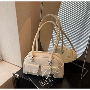Detail of cream lychee leather underarm bag with pearl bow and heart charm