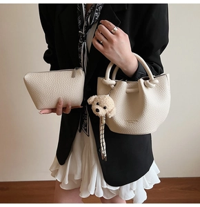 Détail du sac seau crème texture litchi avec breloque chiot et pochette