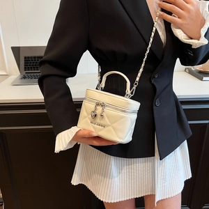 Close-up of a white quilted mini box bag with silver heart zippers and metal handle