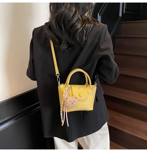 Detail of yellow lychee texture mini bucket bag with teddy charm on a black suit