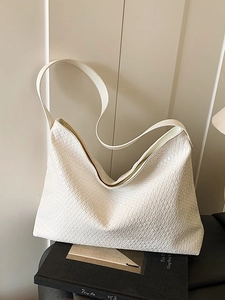 Minimalist white woven leather tote bag with a wide shoulder strap in a modern design