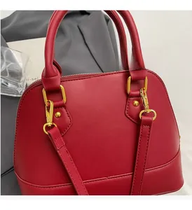 Close-up of wine red shell handbag with polished gold hardware and leather texture
