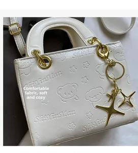 Close-up of beige PU leather handbag with embossed teddy bear patterns and star charm