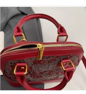 Close-up of smooth gold zipper and embroidery detail on a red shell-shaped handbag