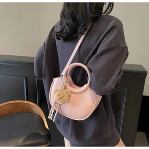 Detail of pink PU leather handbag with cracked texture and a cute plush bear charm