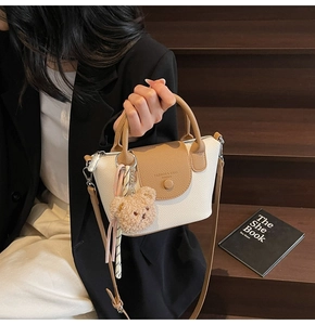 Detail of two-tone bucket bag featuring lychee texture and cute bear pendant charm