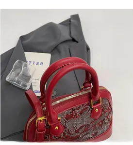 Detailed close-up of a red shell bag with silver embroidery and gold-tone metal hardware