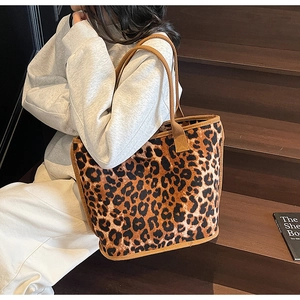 Detailed shoulder view of a large leopard print tote bag with brown woven handles