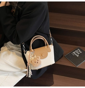 Détail du sac bicolore avec rabat en cuir marron et charmant ours en peluche attaché