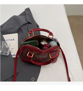 Detail view of burgundy embroidered shell bag showing spacious interior and daily essentials