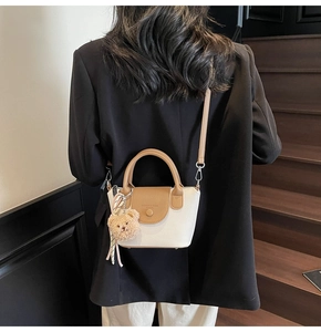 Model wearing a contrasting bucket bag with a plush bear charm on a wooden staircase