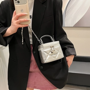 Detail of silver quilted chain bag with heart charm and brand logo worn by a model