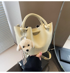 Detailed view of beige bucket bag in lychee leather texture with cute teddy dog charm