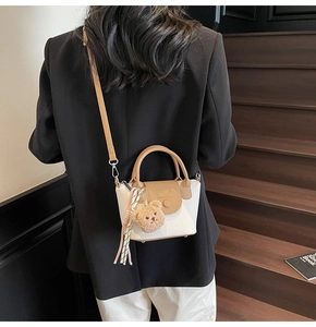 Rear view of a model carrying a vintage contrast bucket bag with a plush bear charm