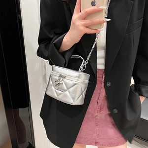 Silver quilted leather crossbody bag with chain strap shown on model's shoulder