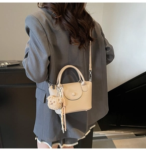 Detailed macro of beige lychee leather tote bag featuring a cute teddy bear charm