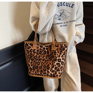Detail view of leopard print canvas tote bag with brown woven handles on model's shoulder