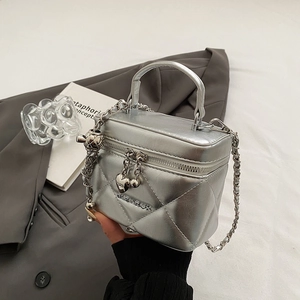 Detailed view of silver quilted box bag with heart zipper and chain strap detail