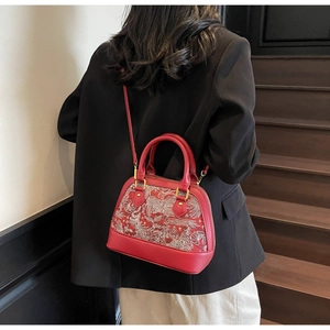 Detail of red shell bag with traditional Chinese floral embroidery and golden hardware