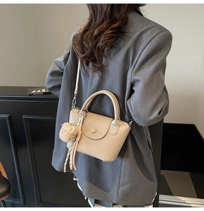 Detail of beige lychee leather bucket bag with plush bear charm and silk scarf handle