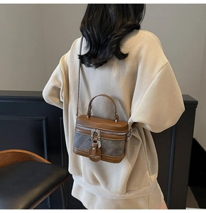 Détail d'un sac boîte contrasté avec bordure en cuir marron et panneaux gris texturés