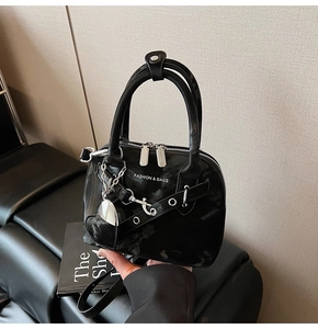 Détail du sac coquille noir avec chaîne argentée, pendentif coeur et ornements